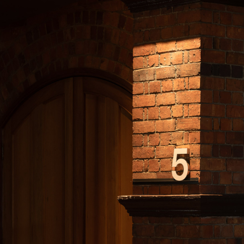 The second-storey foyer outside the Great Hall, with an arched timber doorway, exposed brickwork and warm heritage details.
