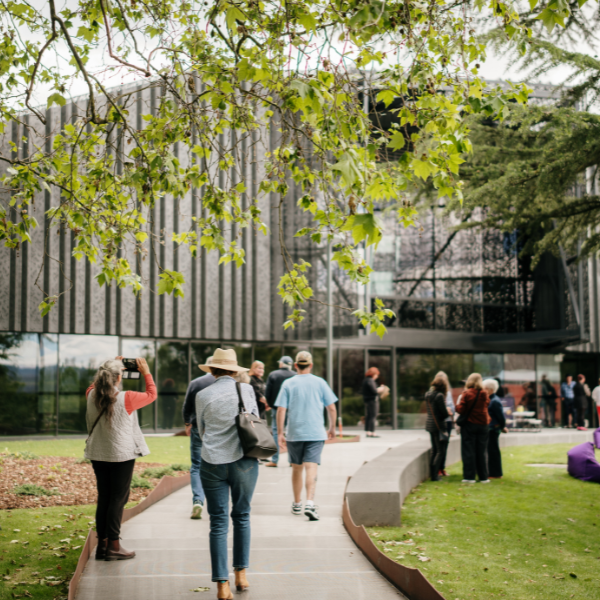 People walking through City Park towards the Albert Hall, with the venue and surrounding trees visible ahead.