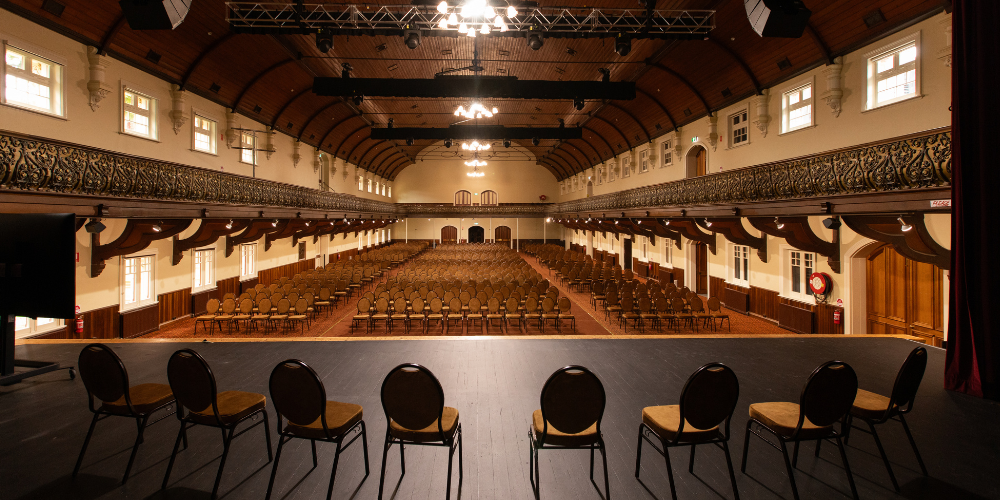 The Great Hall viewed from the stage, with rows of chairs, ornate balconies and the timber vaulted ceiling.